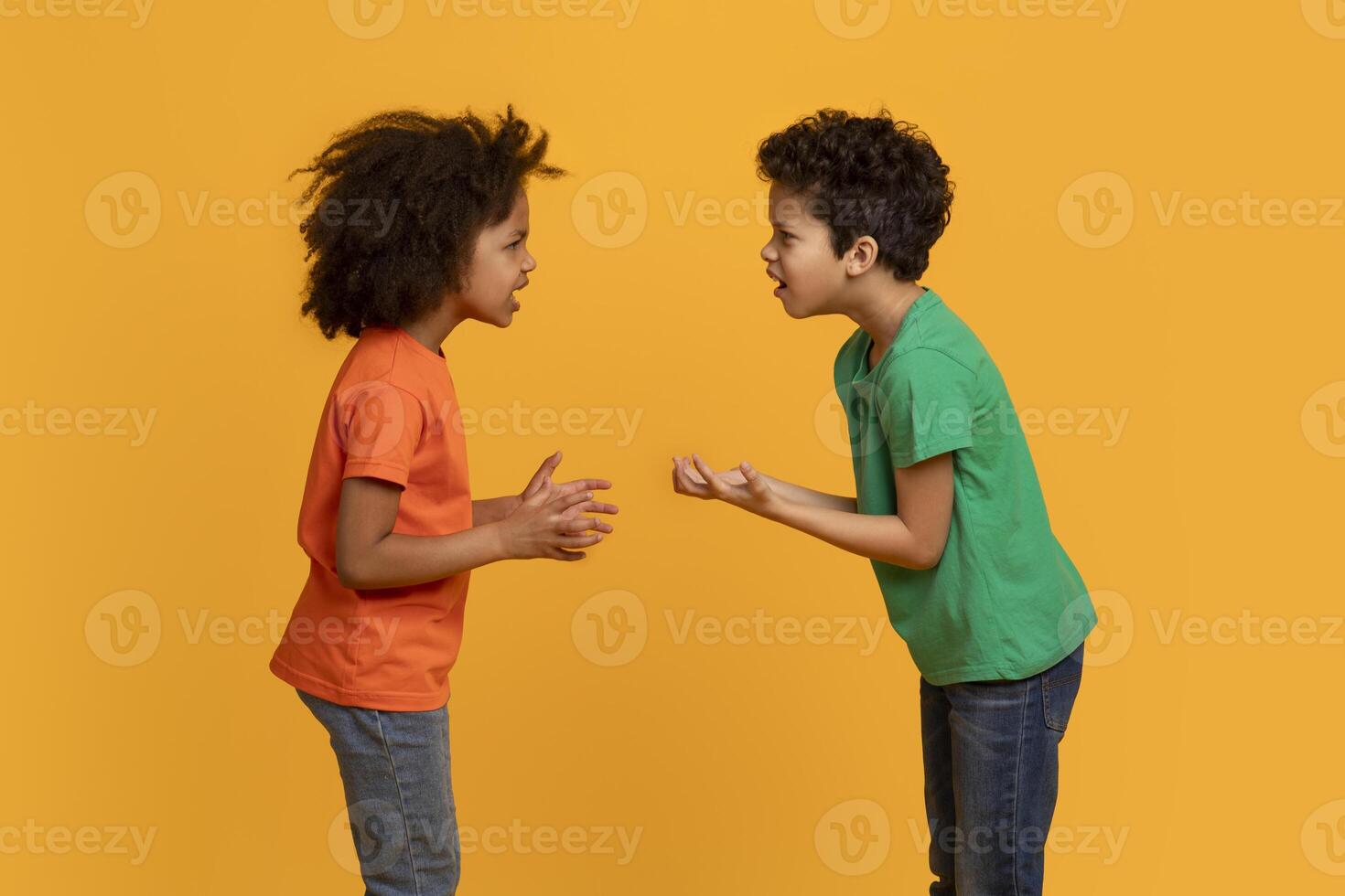 African American young boy and girl are standing face to face with animated expressions, hands gesturing as they appear to be in a playful argument or discussion. photo