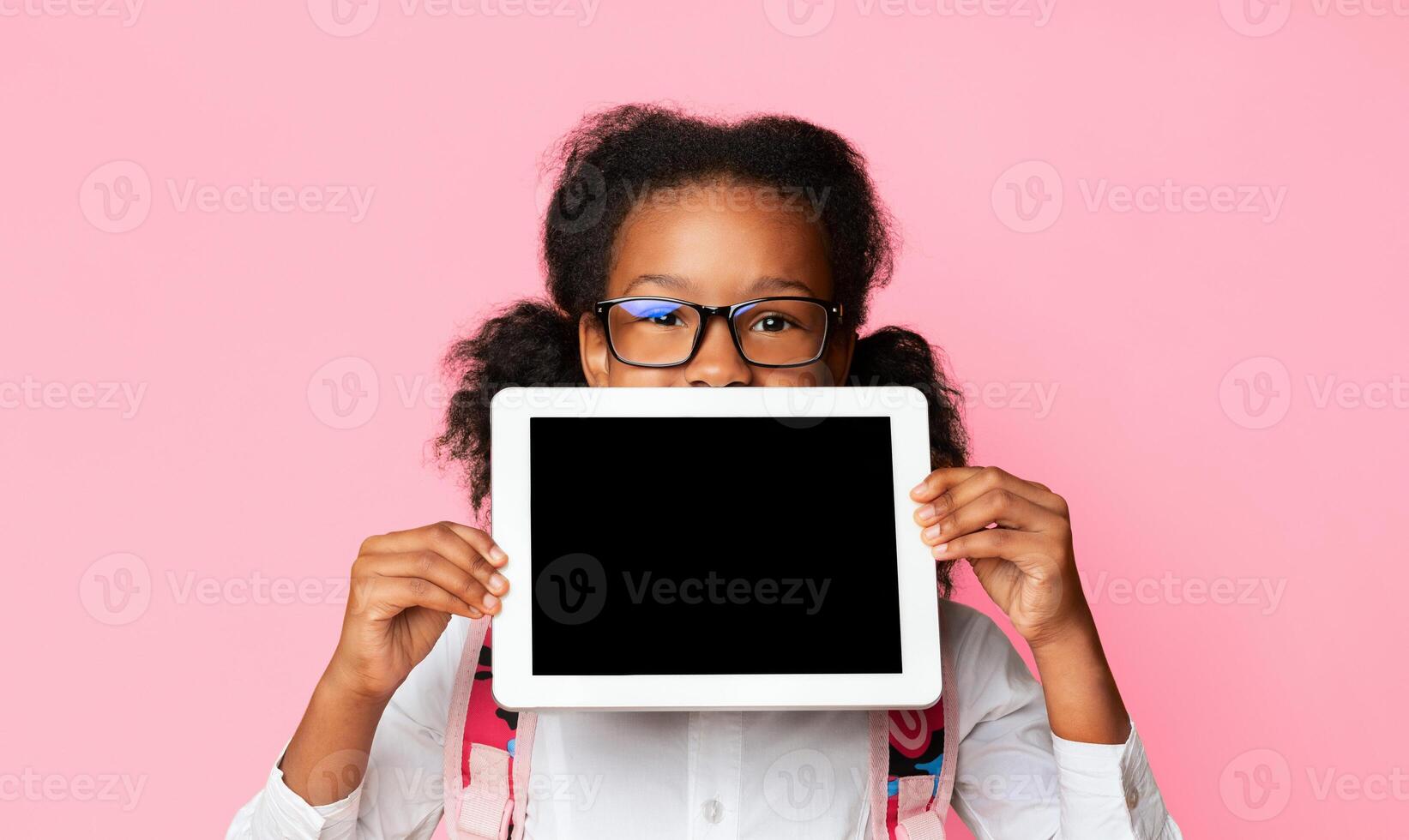 Online School And E-Learning. Schoolgirl Holding Digital Tablet With Blank Screen Recomending Web Classes And Distant Learning On Yellow Background. photo