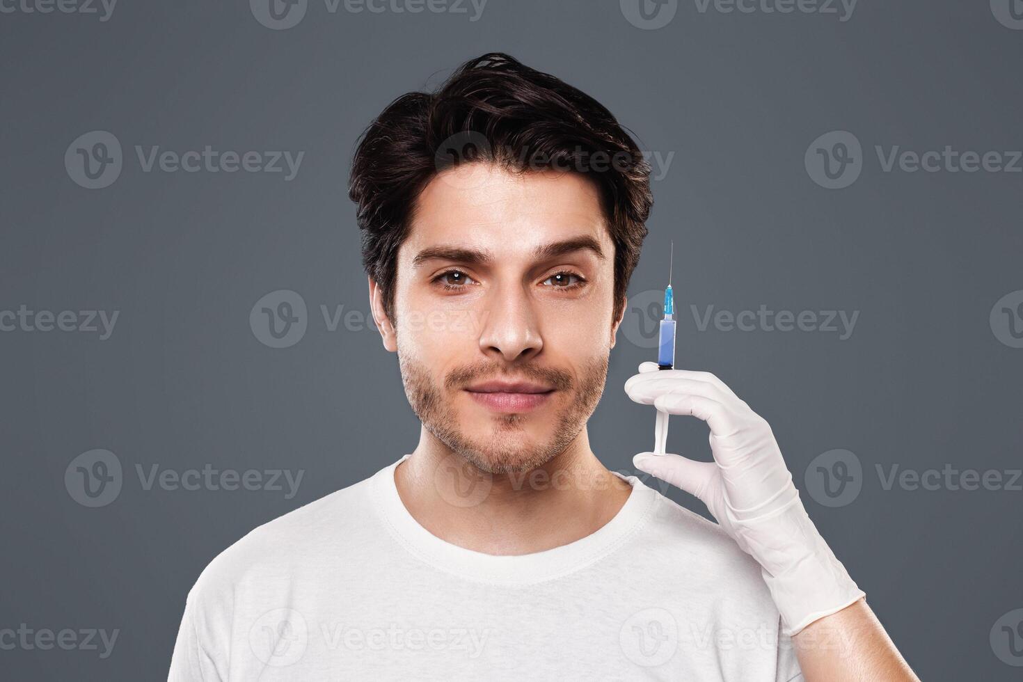 Beautician hands holding syringe with transparent liquid near male face, aesthetic cosmetology and beauty care photo