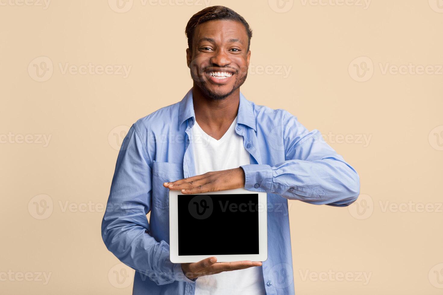 Positive Afro Man Showing Blank Digital Tablet Screen Standing On Yellow Studio Background. Mockup photo
