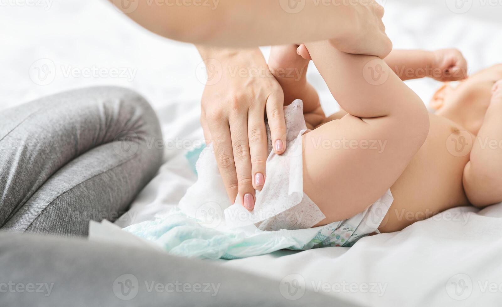 Diaper change. Mother cleaning buttocks of newborn baby with wet wipes photo