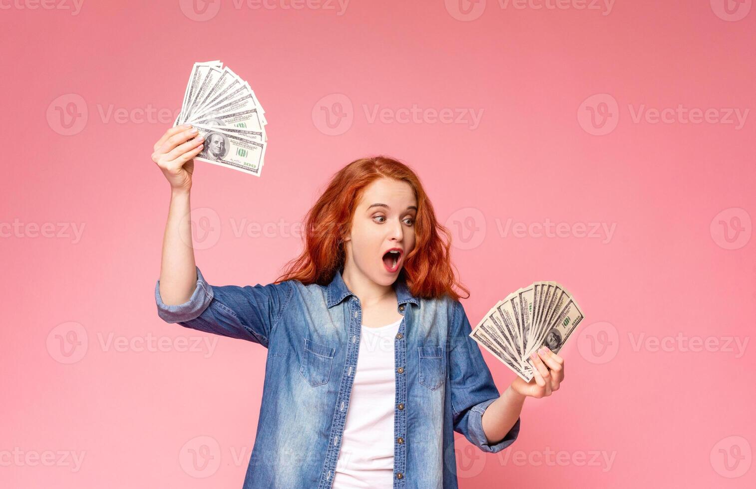 A woman standing, holding a bunch of money in her hands. She is looking at the money with a serious expression. The money is crumpled and a mix of bills and coins. photo