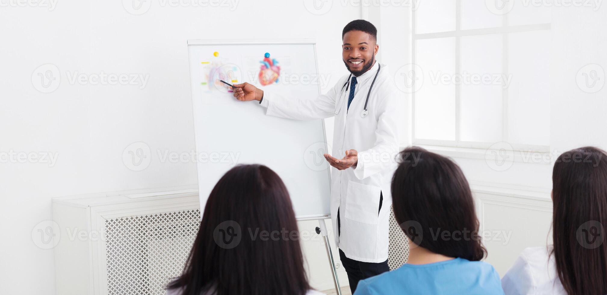 African-american cardiologist giving information to interns at medical seminar in hospital photo
