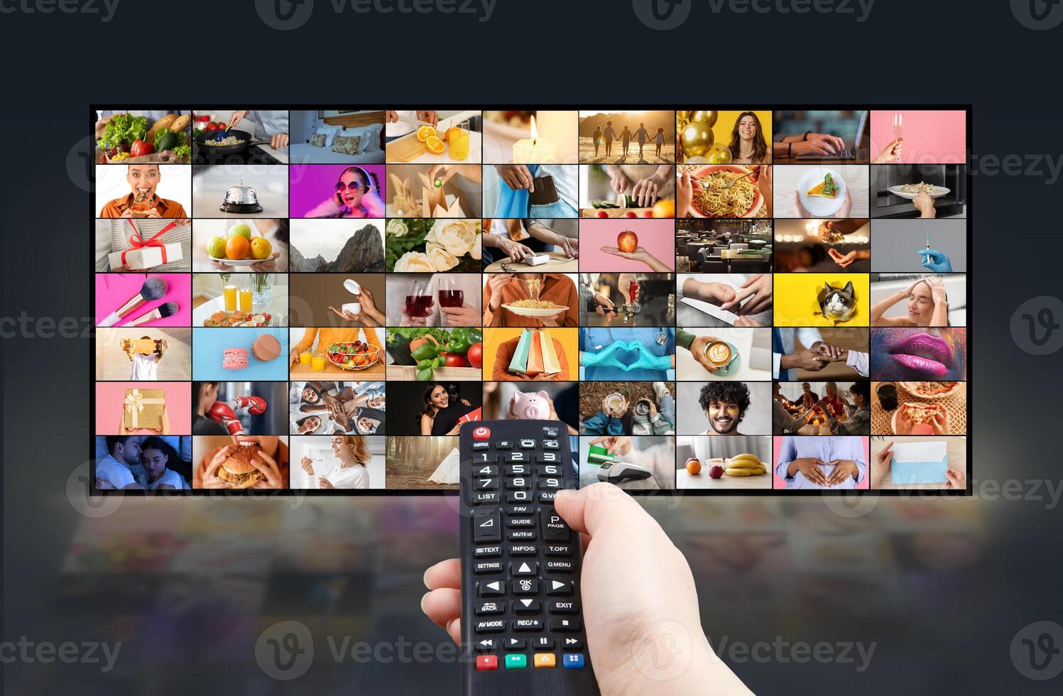 A persons hand holds a remote control and points it towards a large flat screen television. The TV screen displays a variety of colorful, diverse content in a grid format photo