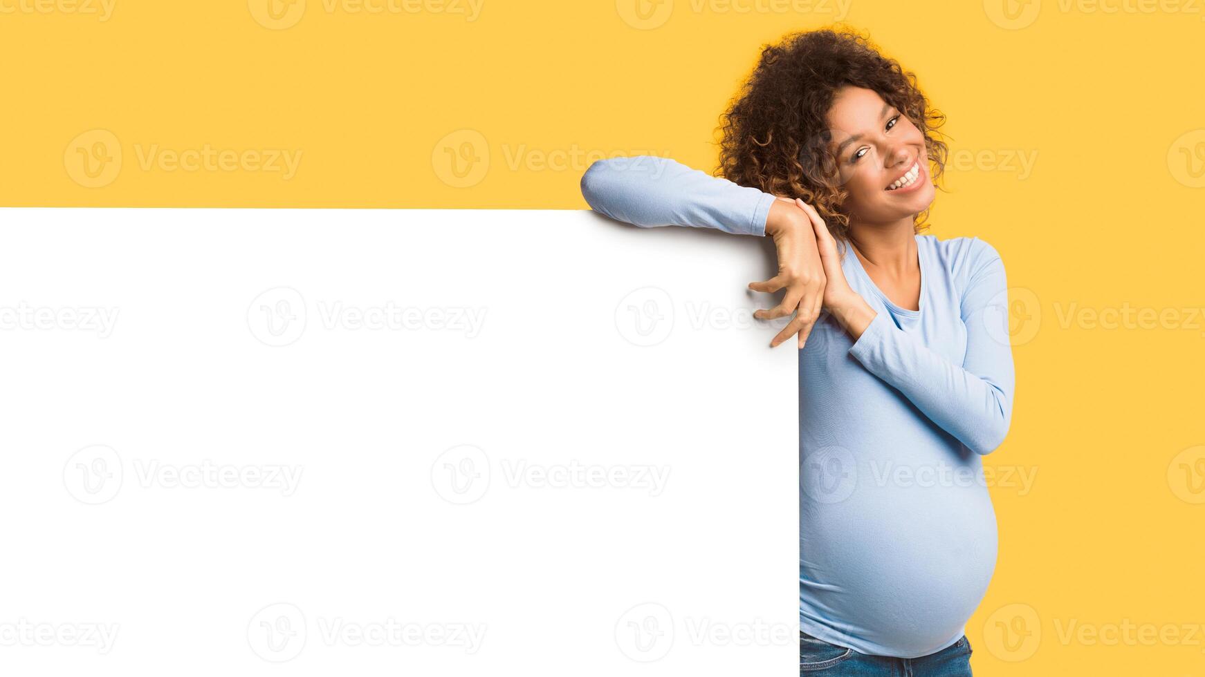 Great offer. Happy afro pregnant woman near blank poster over white background, panorama with empty space photo