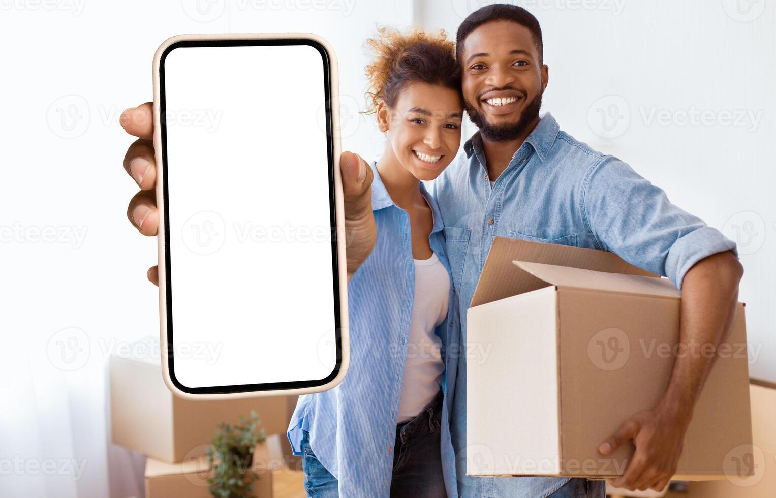 Own House. Happy Black Couple Showing Key Holding Moving Box And Hugging Standing In New Home. photo