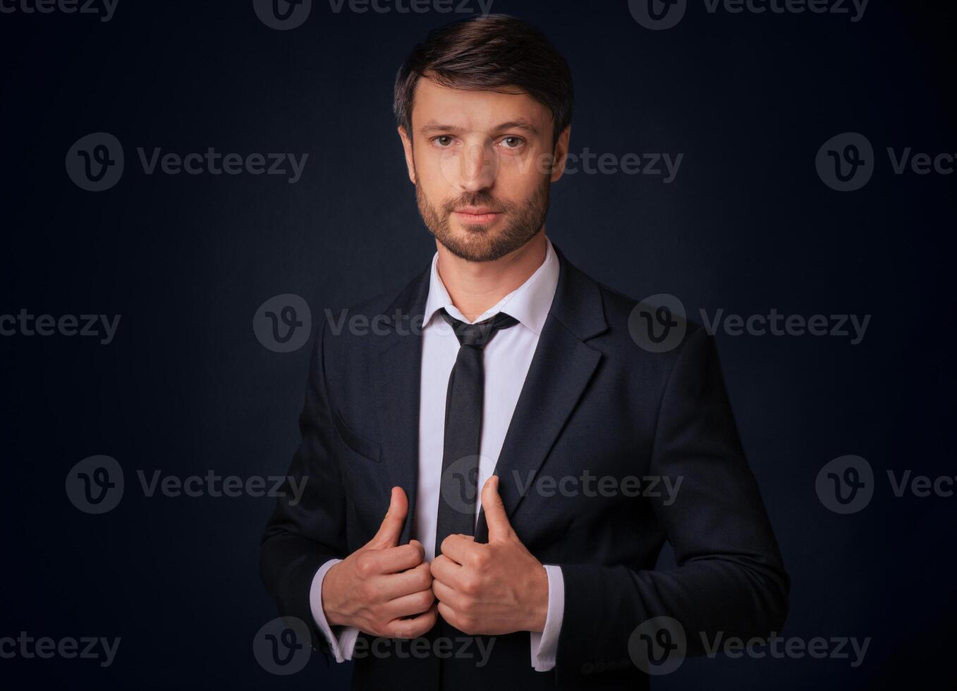 Confident Businessman Looking At Camera Holding Jacket Lapels Posing Over Black Background. Studio Shot photo