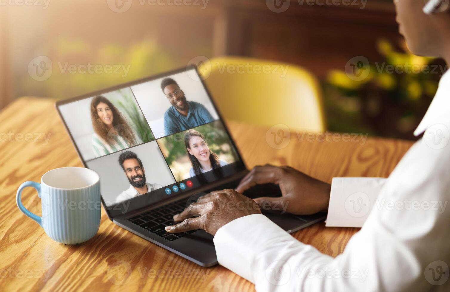 Black woman actively engaged with a laptop, with a group of people displayed on the screen. The individual appears focused and immersed in the digital interaction. photo
