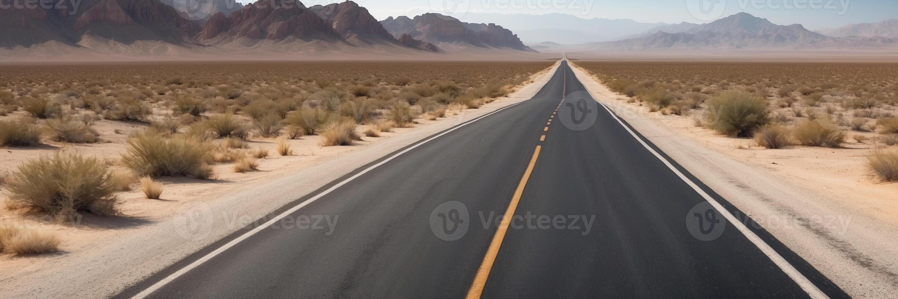 An empty road in the desert with mountains in the background photo