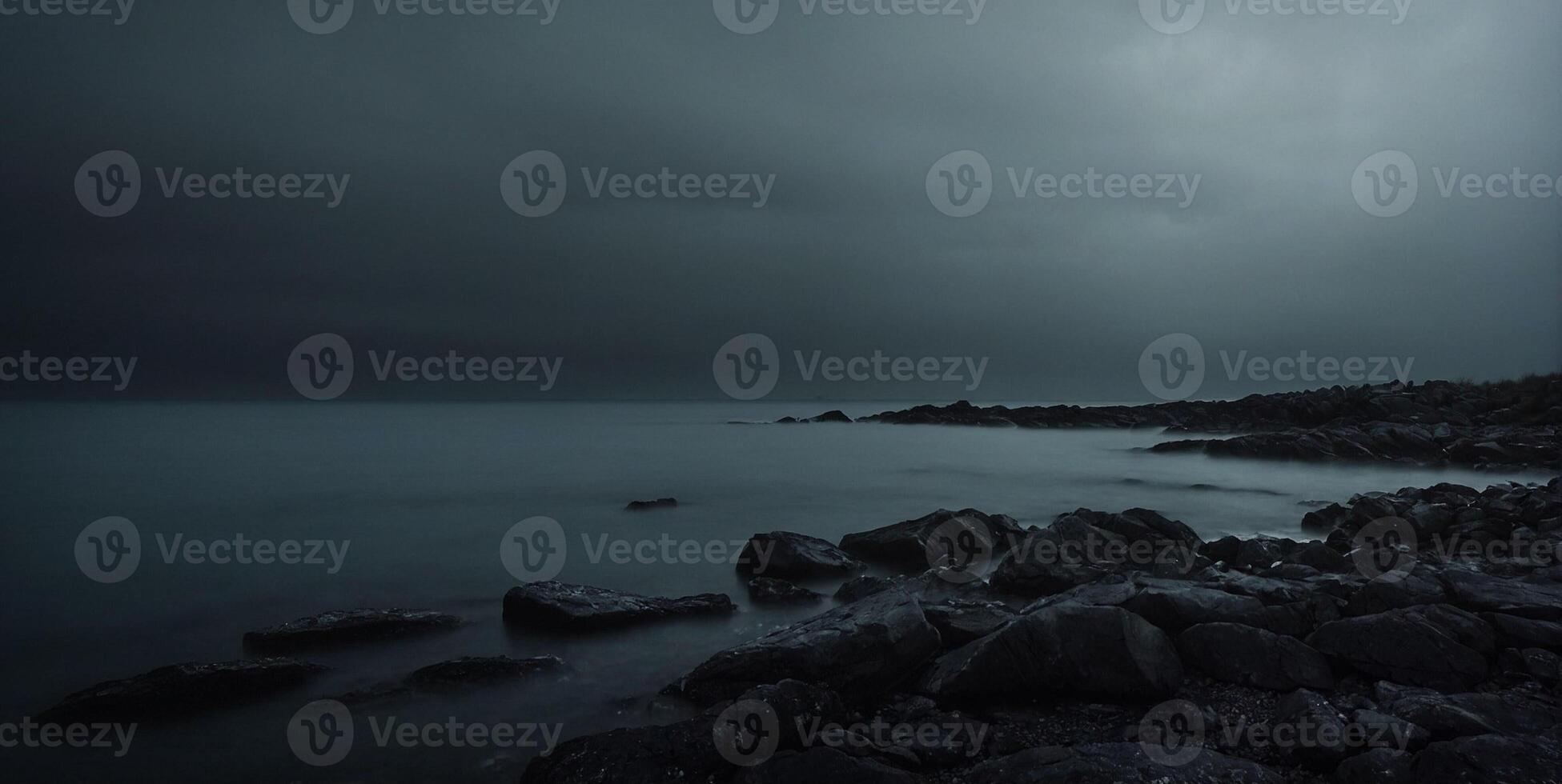 A dark stormy night on the beach with rocks and water photo