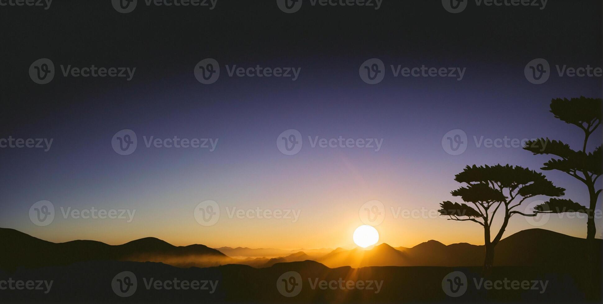 A silhouette of a tree and the sun setting over mountains photo