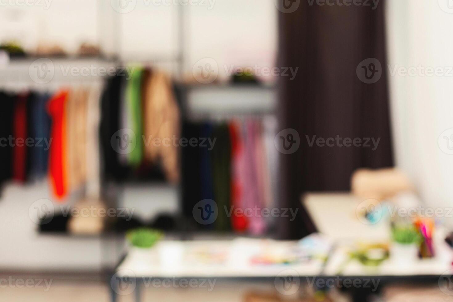 A blurry view of a room filled with various racks displaying clothes. The image captures the cluttered yet organized arrangement of garments in the room. photo