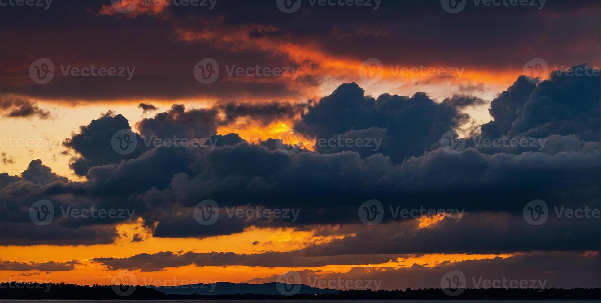A sunset over the water with clouds and mountains in the background photo