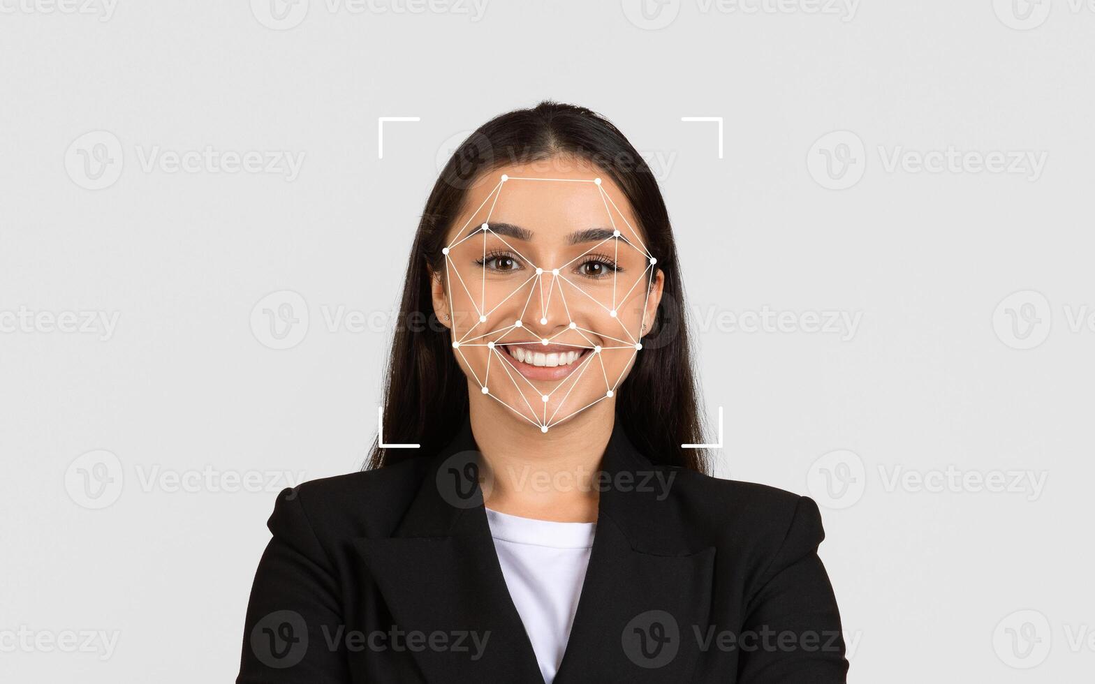 A woman smiles confidently while a facial recognition grid overlays her face in a neutral background. photo