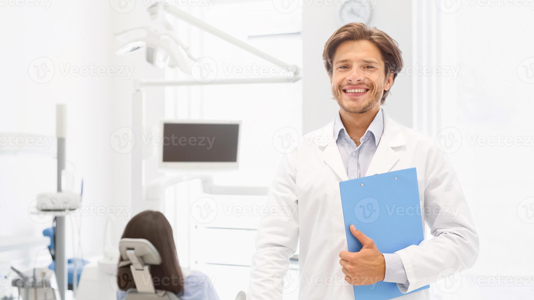 Visit my clinic. Handsome dentist keeping smile on his face and holding folder over cabinet background, empty space photo