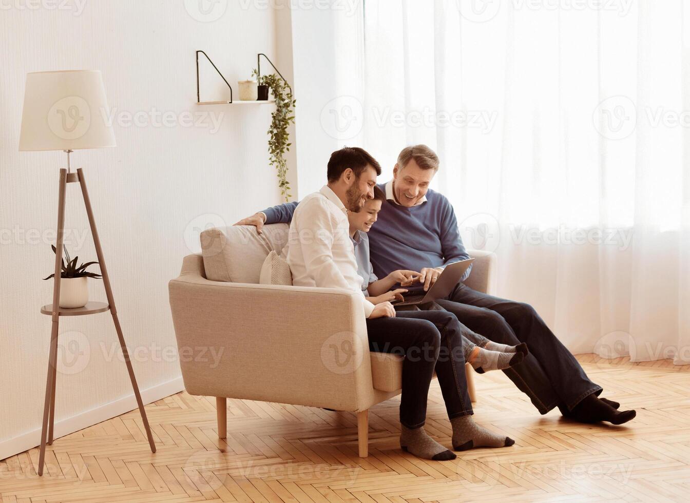 Cheerful Boy, Father And Grandfather Using Laptop Computer Sitting Together On Couch At Home. Empty Space photo