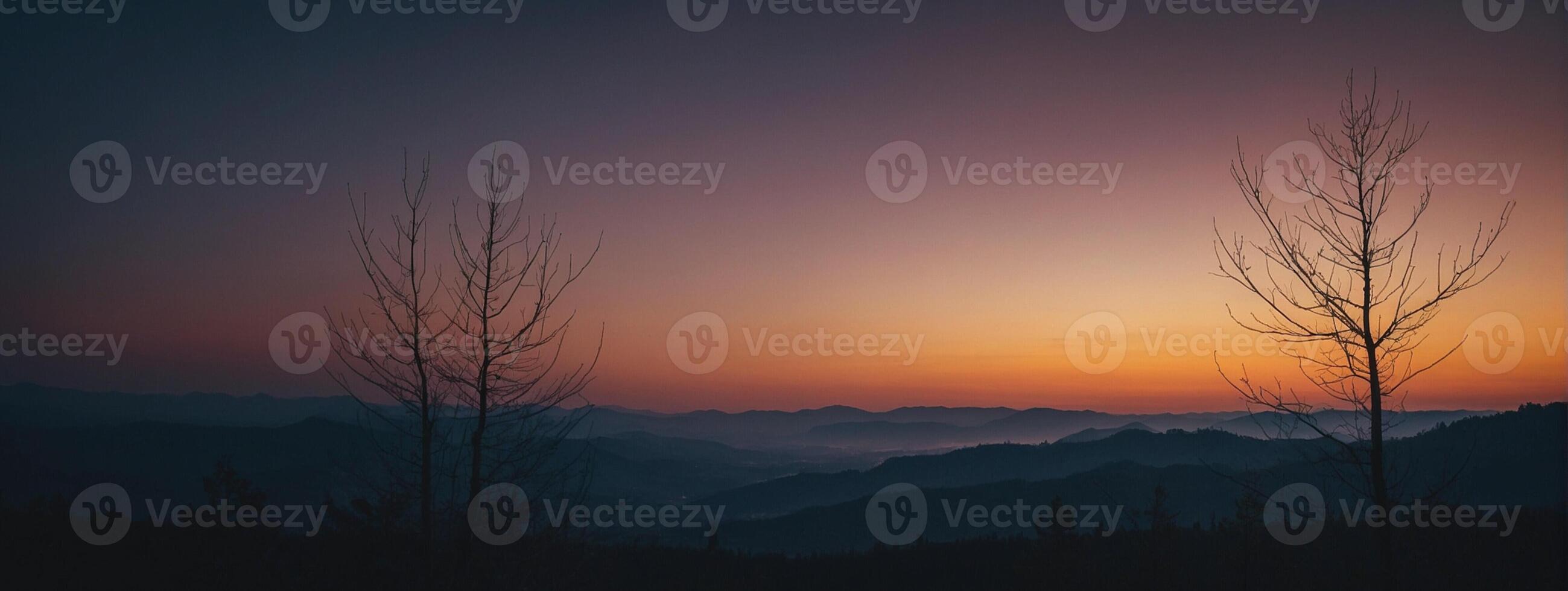 Silhouette of trees and mountains at sunset photo