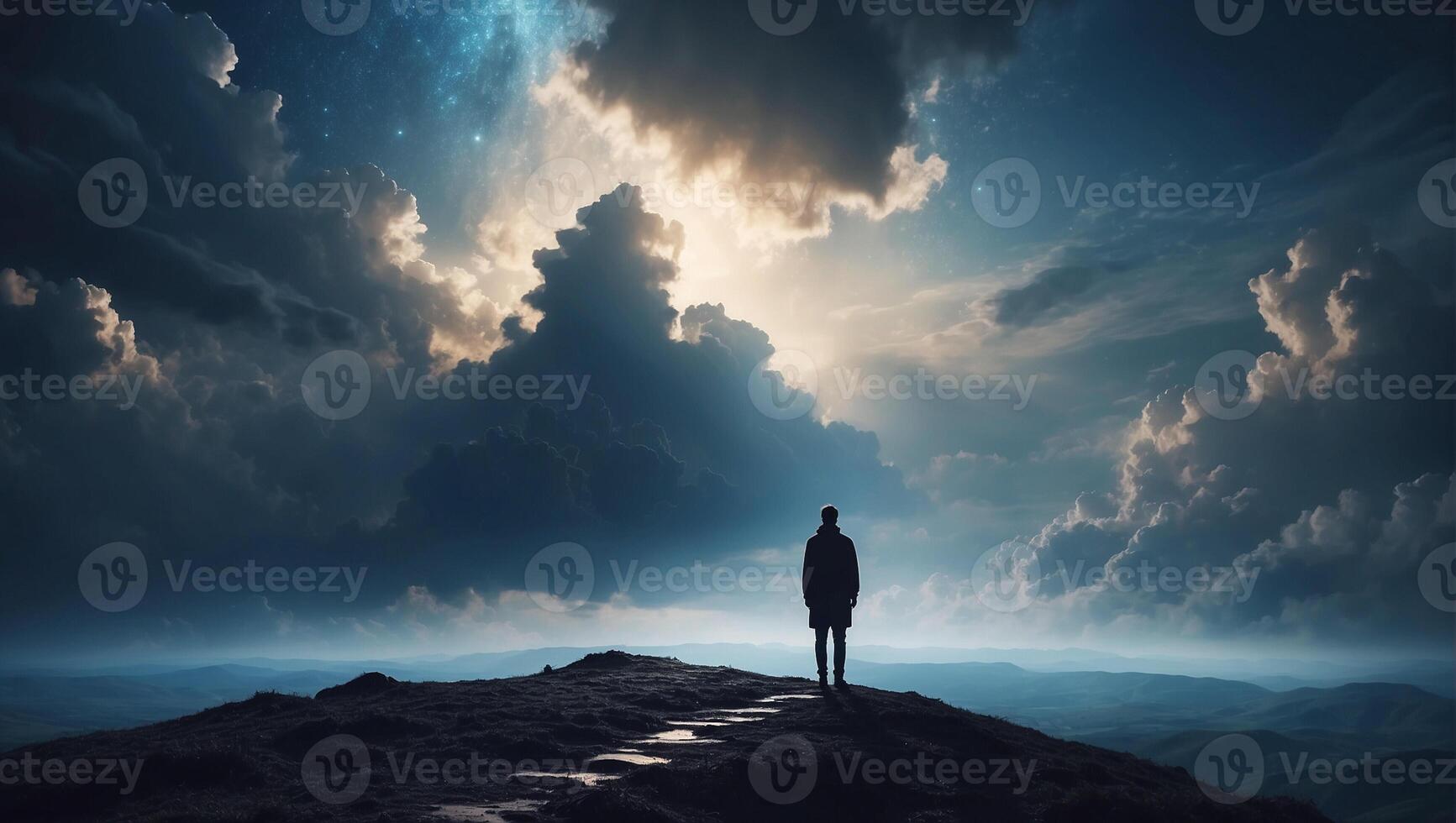 A man standing on top of a mountain looking at the sky photo