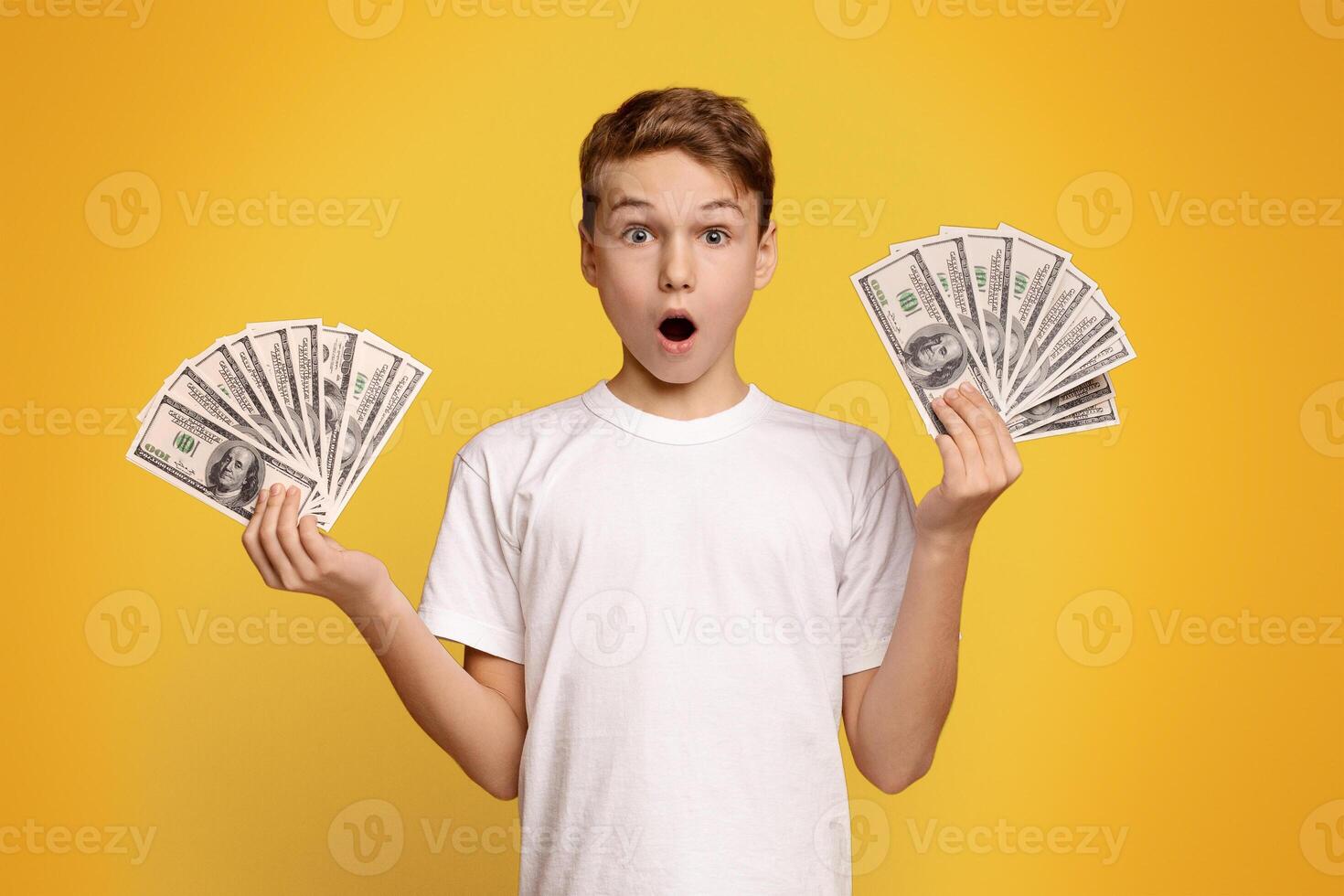 Finance, investment and money saving. Excited boy man holding lots of dollars, orange studio background photo