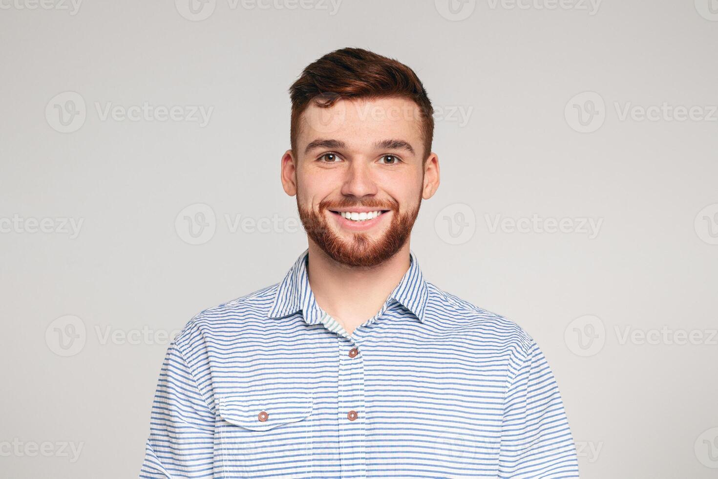 Portrait of smiling bearded millennial guy wearing casual shirt posing isolated on beige studio background photo
