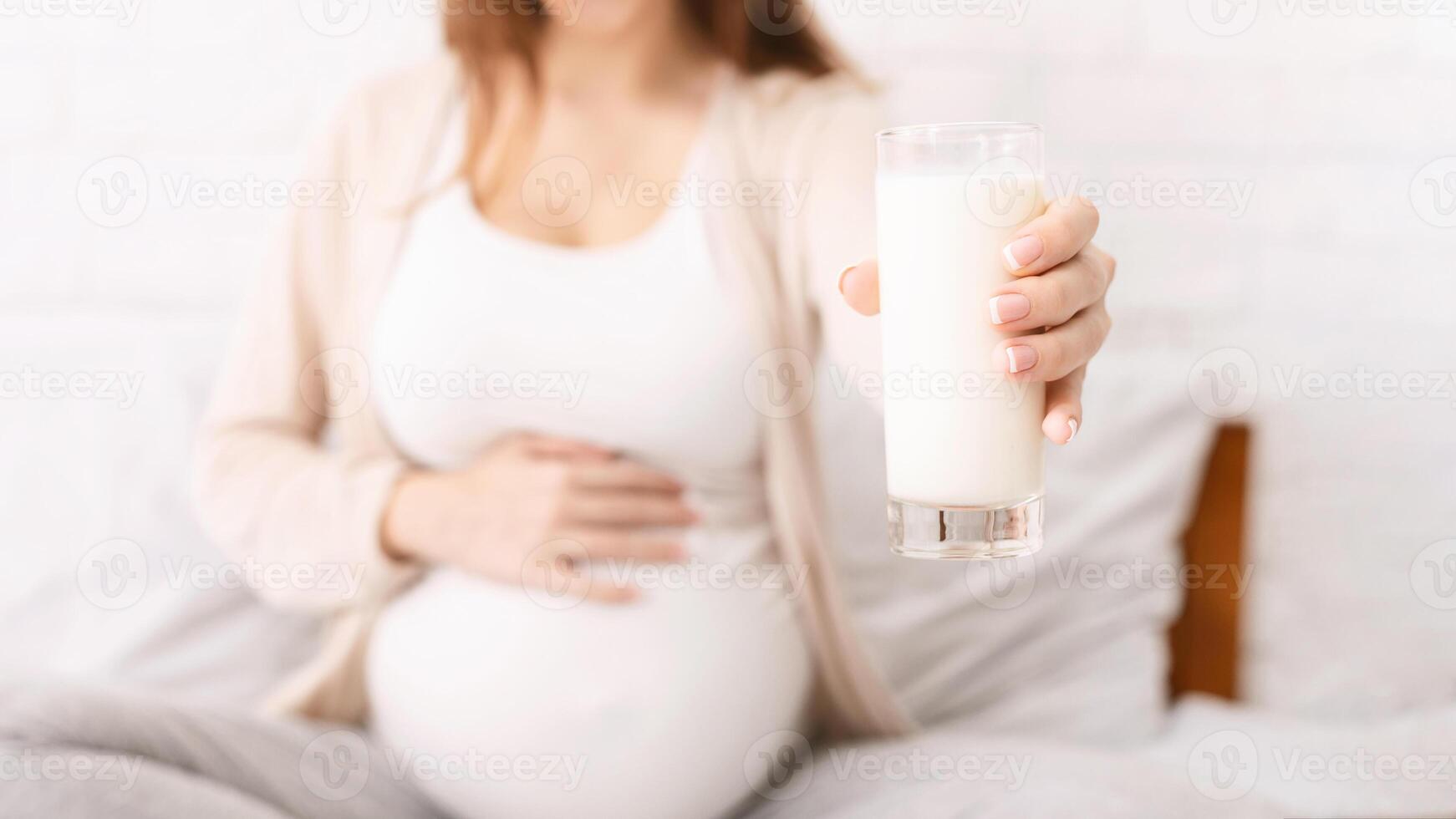 Lactation and breastfeeding concept. Pregnant woman offering glass with fresh milk on camera, conceptual photo