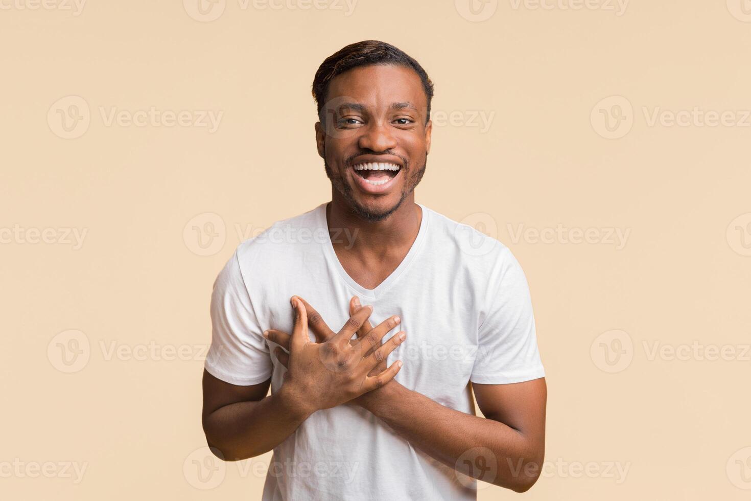 Positive African American Man Laughing All Heartedly Touching Chest Looking At Camera Standing Over Yellow Background. Studio Shot photo