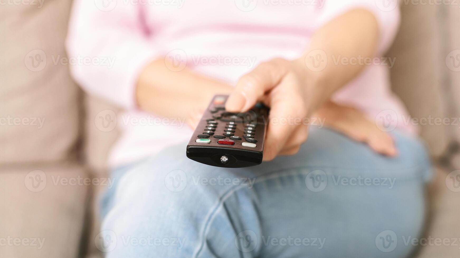 Senior woman watching tv and changing channel with remote control at home, close up photo