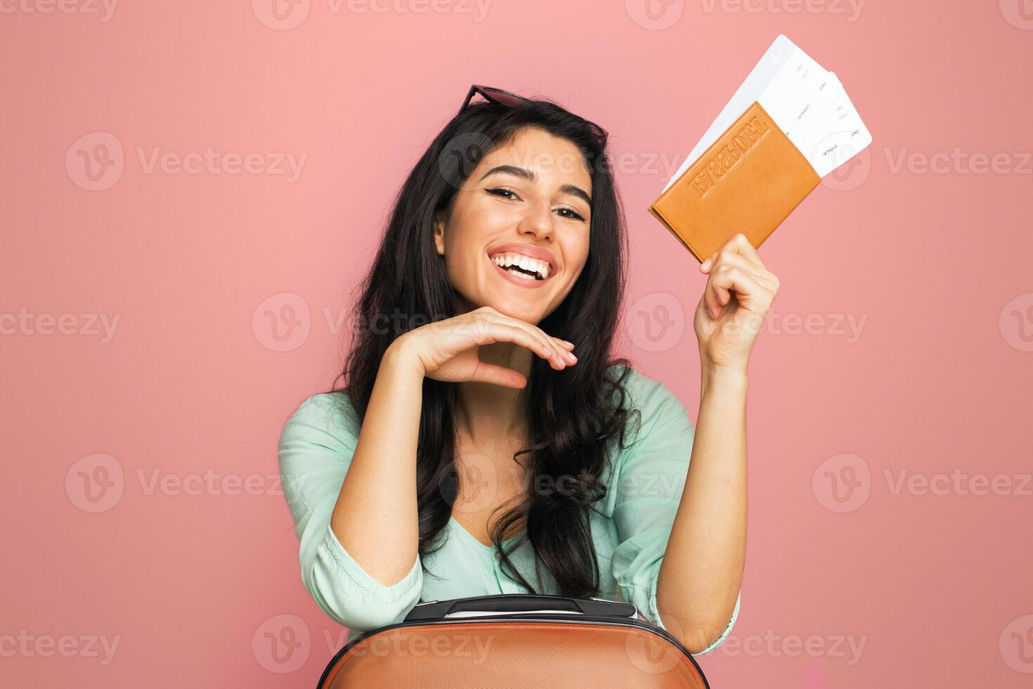 A cheerful young middle eastern woman is holding up her passport and boarding pass as she prepares to embark on an adventure. photo