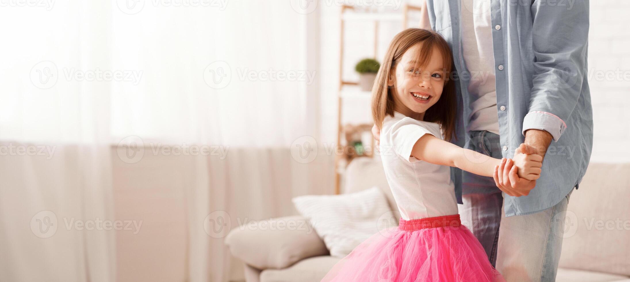 Close up of little princess staying on father's feet, dancing together at home photo