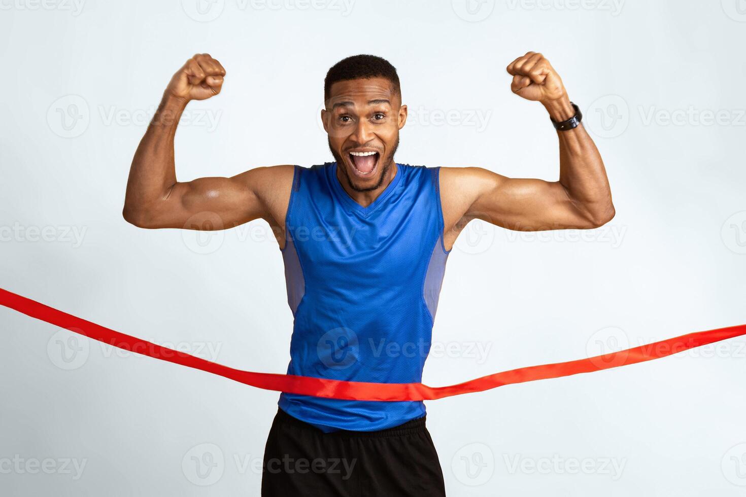 Winner. Excited black sportsman running, crossing the finish line breaking the tape, yellow studio background photo