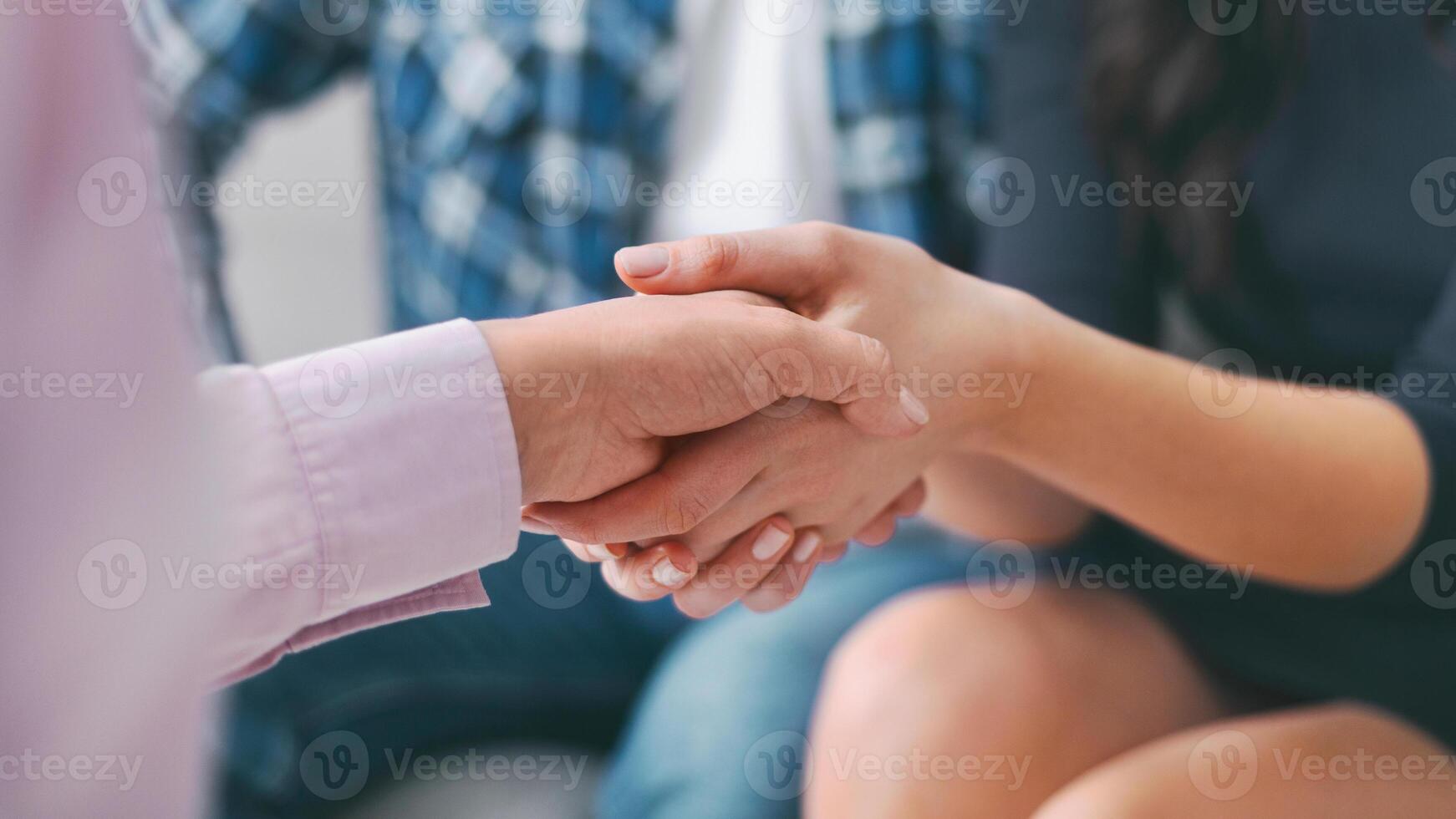 A closeup image of two people shaking hands during a meeting. The image is focused on the hands, with the rest of the bodies blurred in the background, cropped photo
