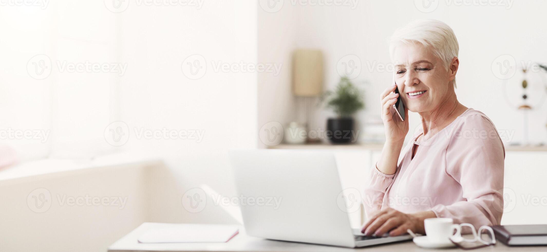 Senior business woman working from home, discussing project with client, using laptop, panorama with empty space photo