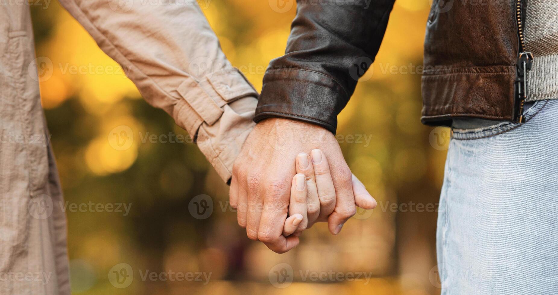 Hands of couple in love walking by autumn forest, close up photo