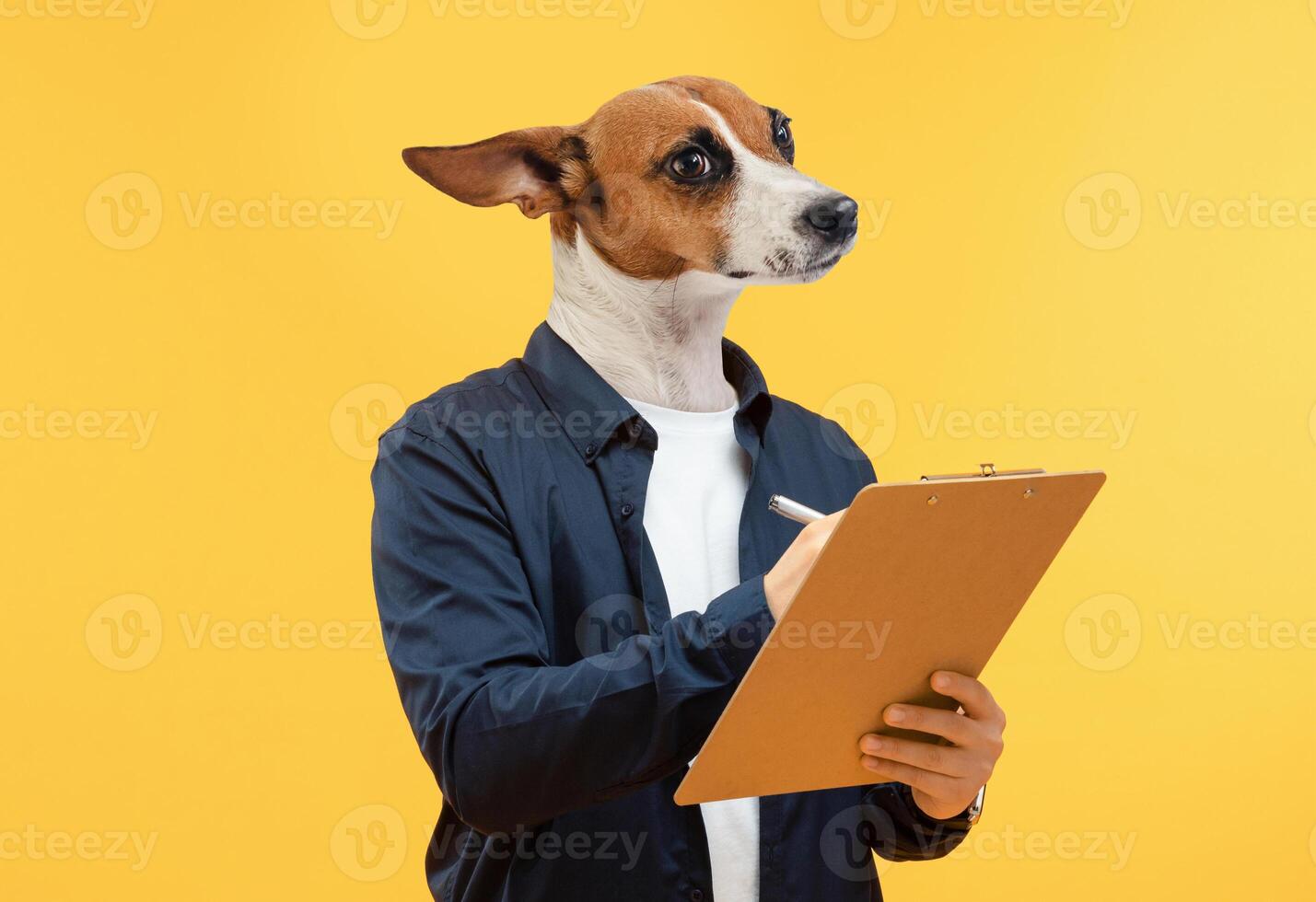 A dog, wearing a blue shirt, holds a clipboard in its paws and writes with a pen. The dog is in front of a yellow background. Its head is cocked to the side, and it looks focused on the clipboard. photo
