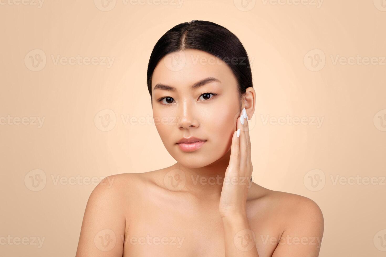 Asian Young Lady Touching Her Beautiful Skin Enjoying Result Of Successful Facial Skincare Routine, Posing With Bare Shoulders Looking At Camera Over Gray Background. Studio Shot photo