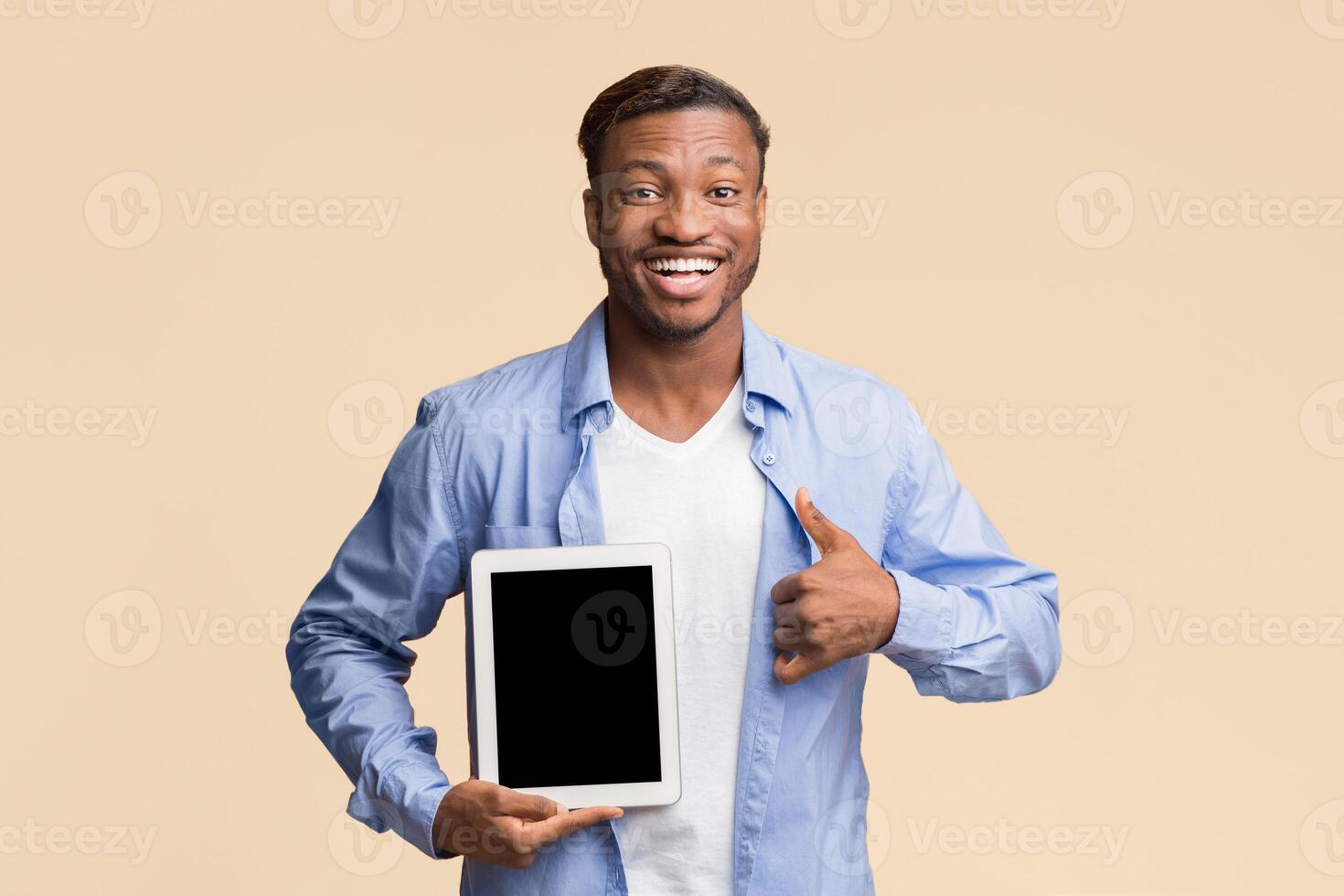 Cheerful Afro Man Showing Empty Tablet Screen Gesturing Thumbs Up Smiling At Camera Standing Over Yellow Background. Mockup, Studio Shot photo