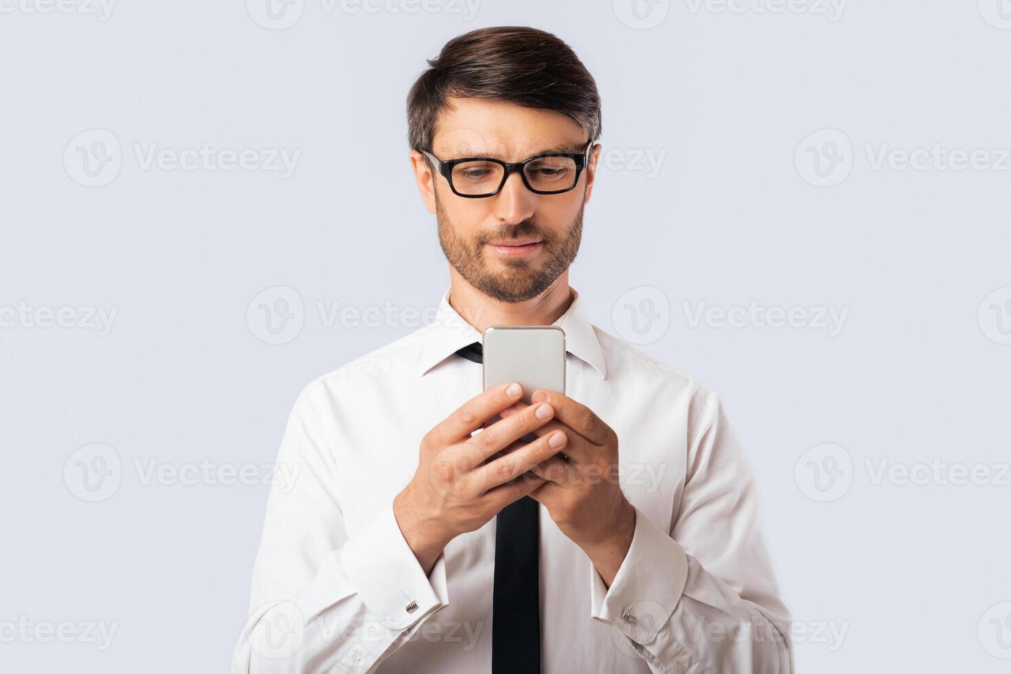 Business App. Serious Businessman Using Smartphone Standing Over White Studio Background. Copy Space photo