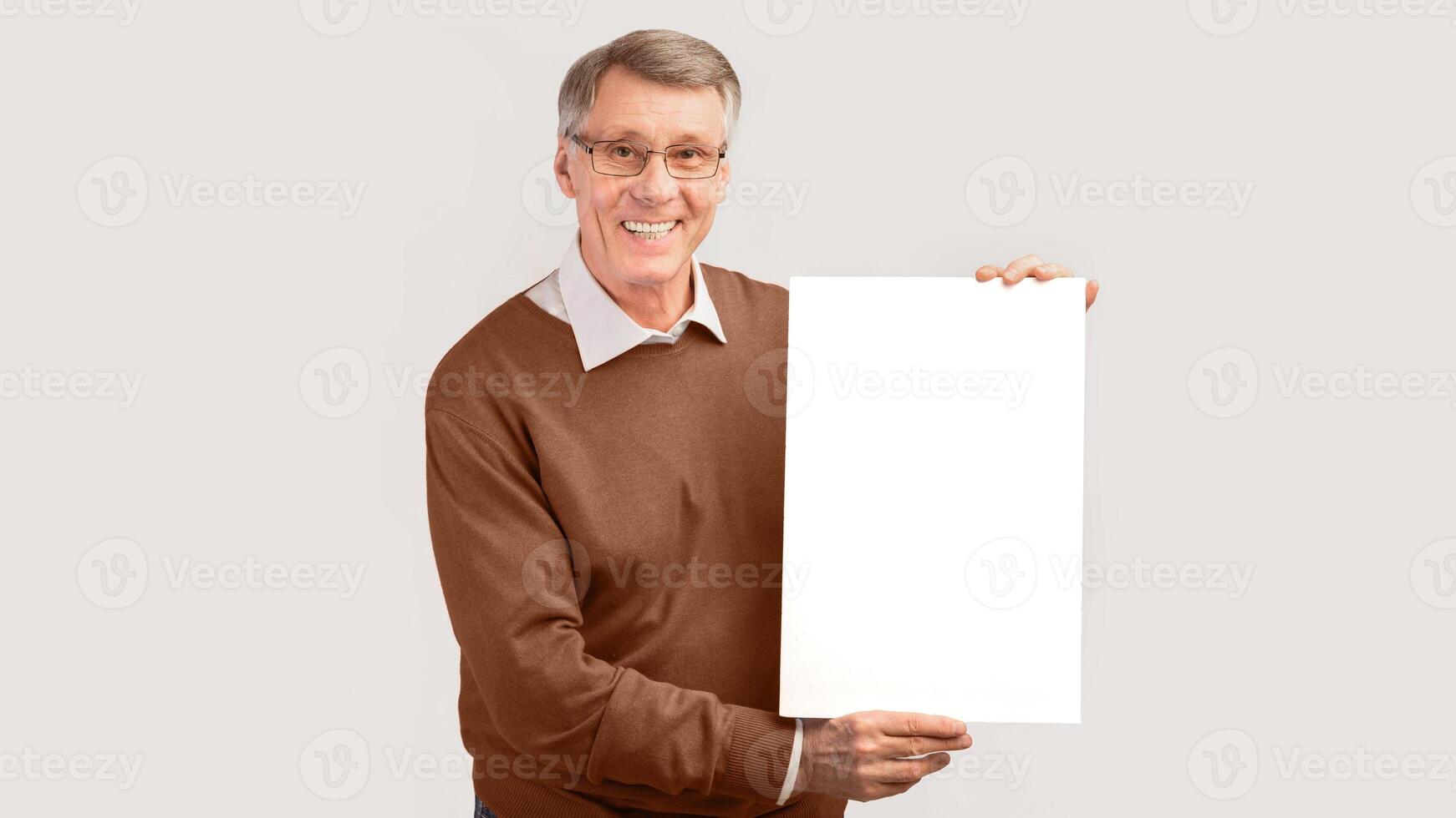 Cheerful Elderly Man Holding Blank Poster Advertising Something Standing On White Background. Studio Shot, Mockup, Panorama photo