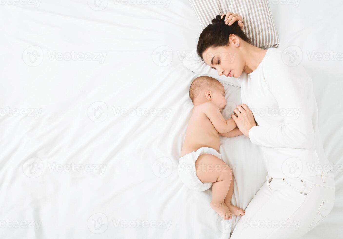 Mother and child connection. Young woman sleeping and touching her baby's hand, top view with free space photo