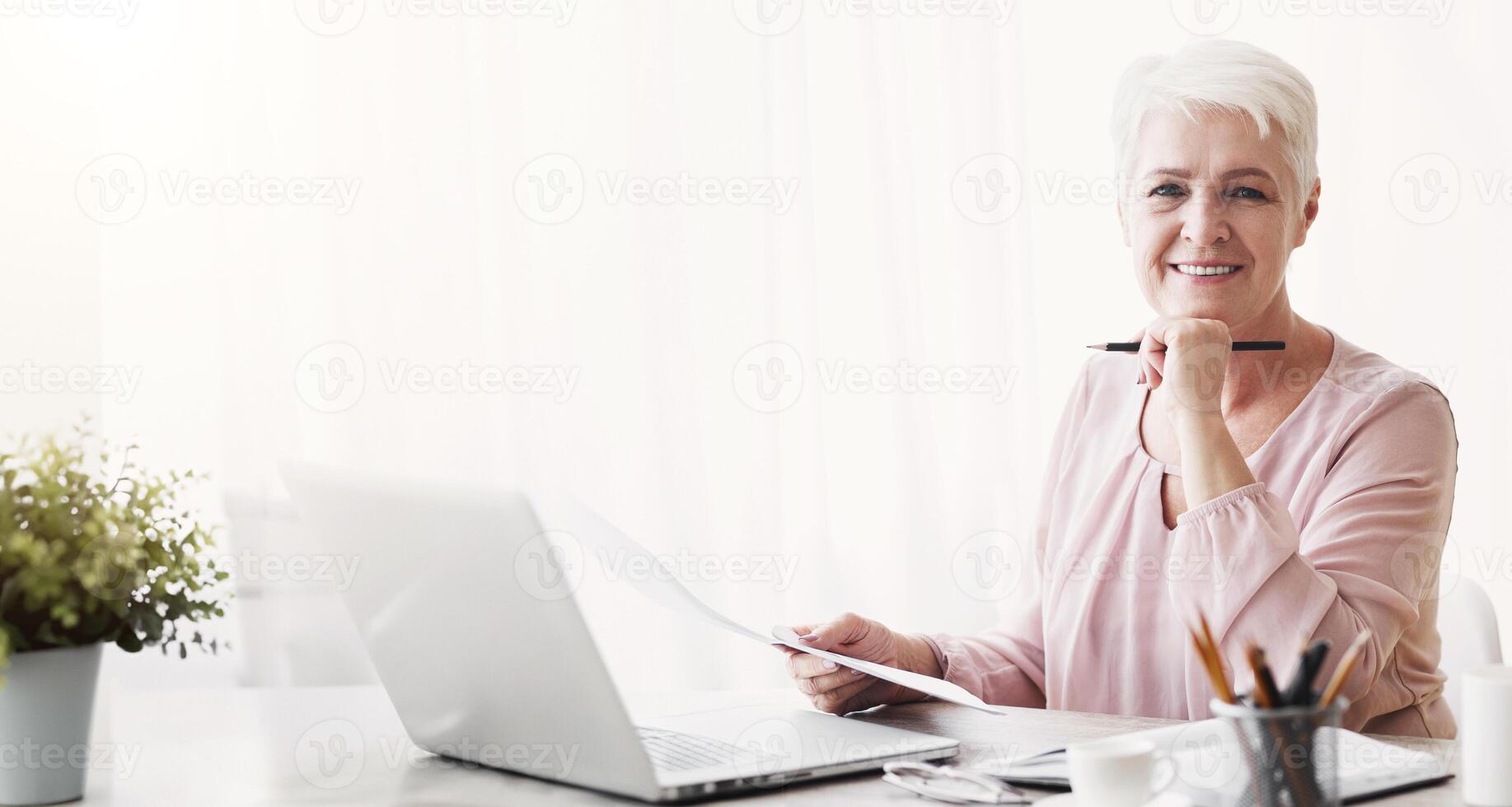 Happy senior business lady working with documents at home, editing text, copy space photo