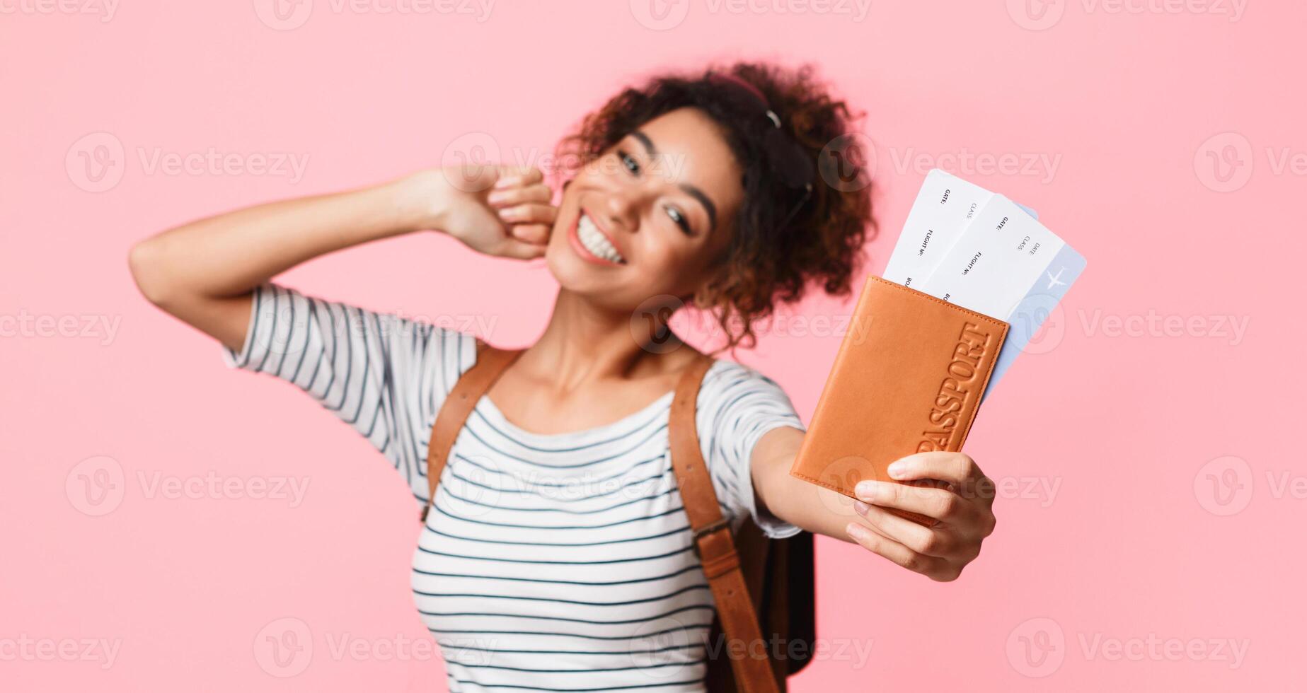 Happy woman showing passport and tickets over pink background, closeup photo