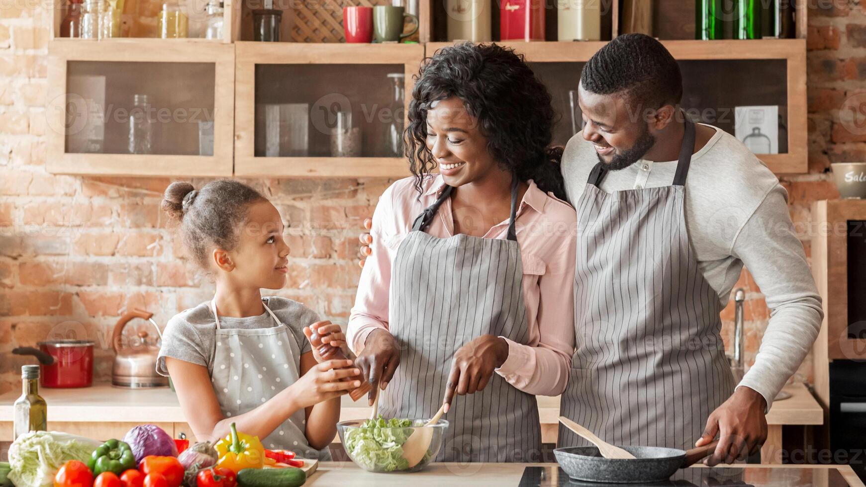 Afro little girl seasoning veggies salad, cooking with parents healthy food at home, panorama with free space photo