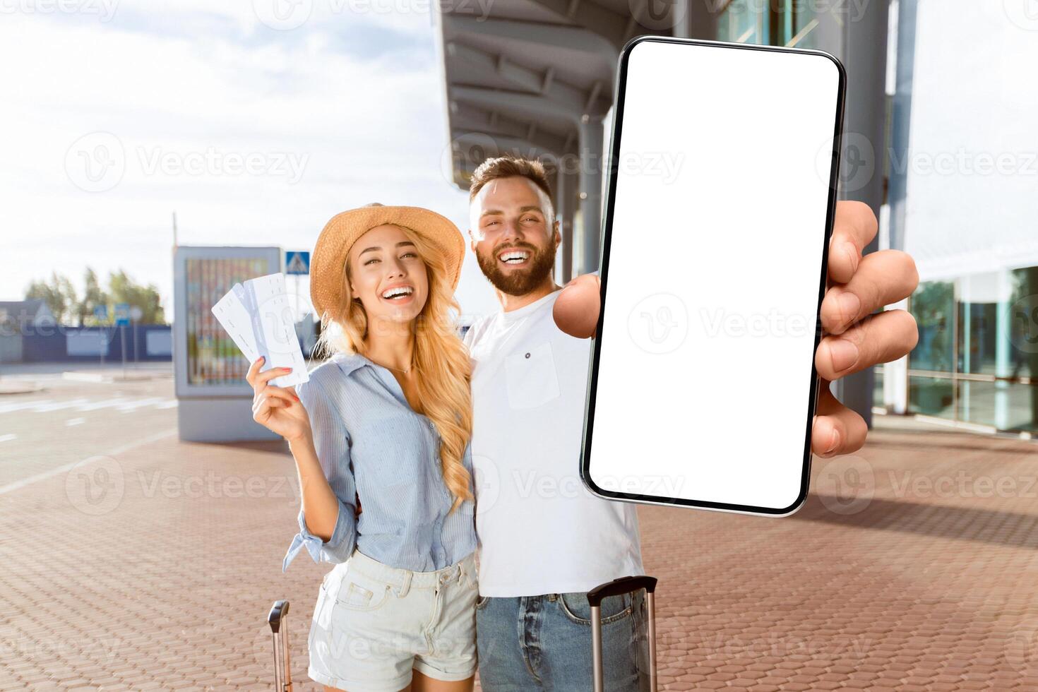 Travel concept. Loving couple going on vacation and holding tickets against airport building photo