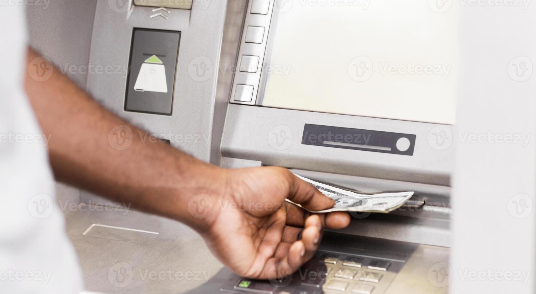 A persons hand reaches into an ATM and retrieves a stack of cash. photo