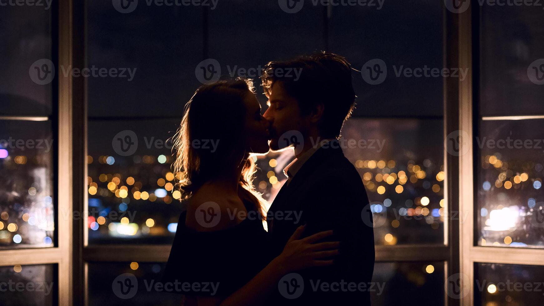 Couple in love kissing on panoramic window background overlooking night city. Love, relationships, affection concept photo