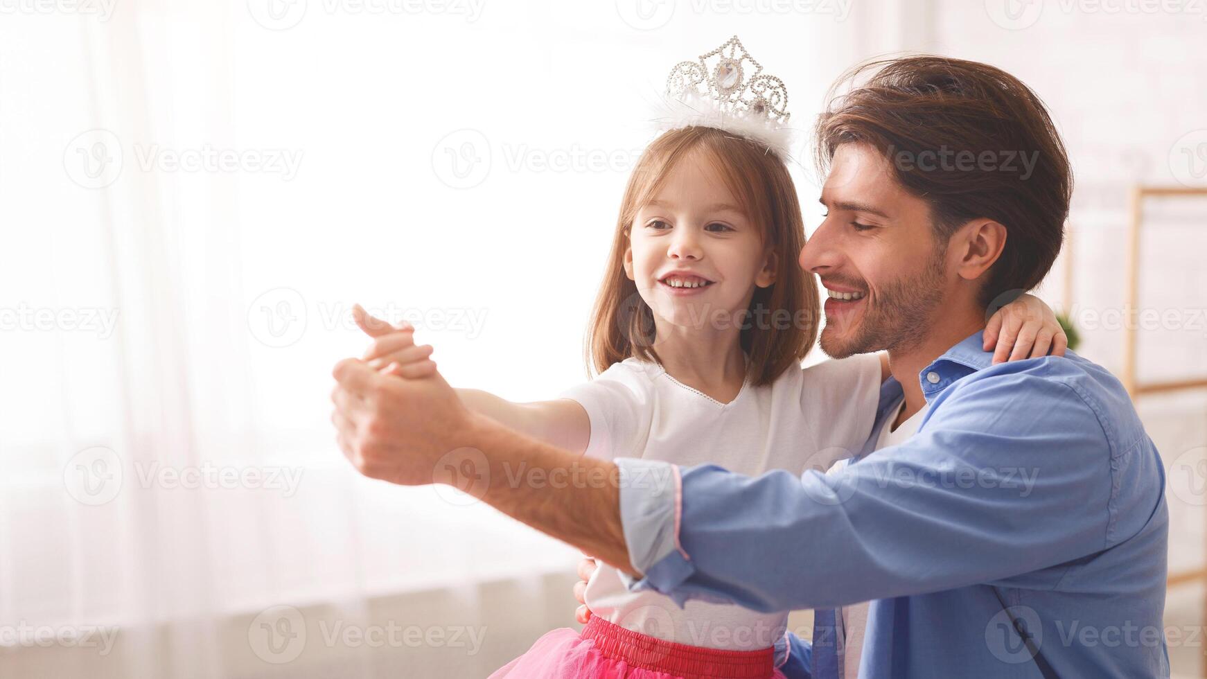 Close up of handsome cheerful dad dancing with his princess little daughter indoor, happy to be father, copy space photo