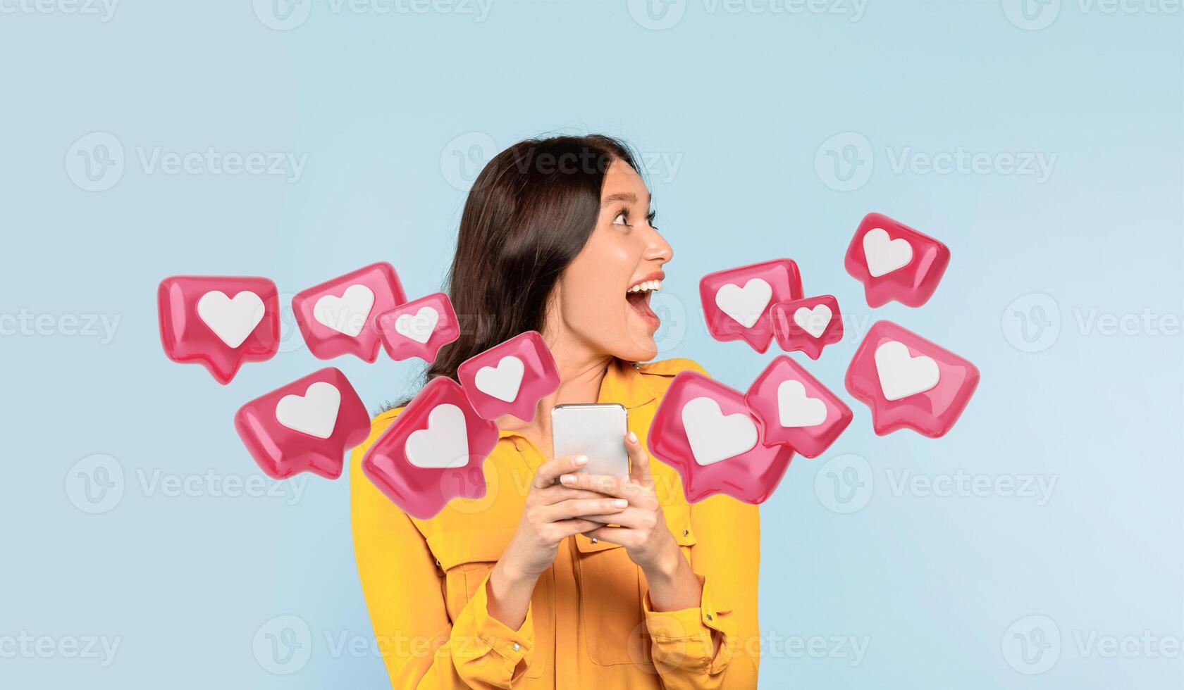 Excited woman holding a smartphone with an astonished expression, as if reacting to love message from boyfriend, looking aside at copy space, against clean blue background photo