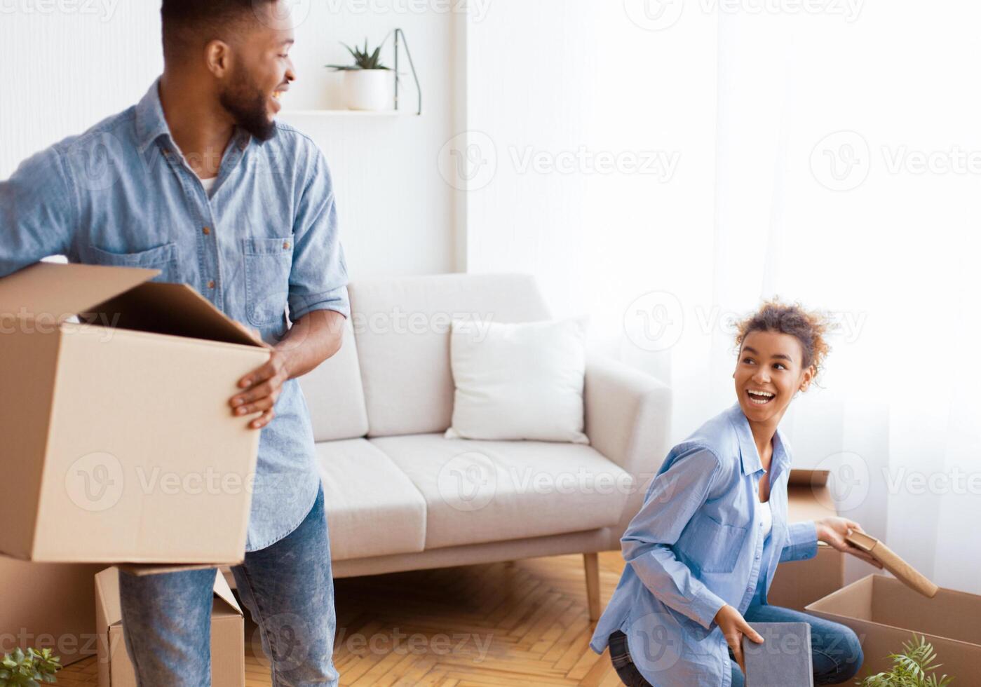 Relocation Concept. Excited Young Afro Couple Packing Moving Boxes Indoor. Selective Focus photo