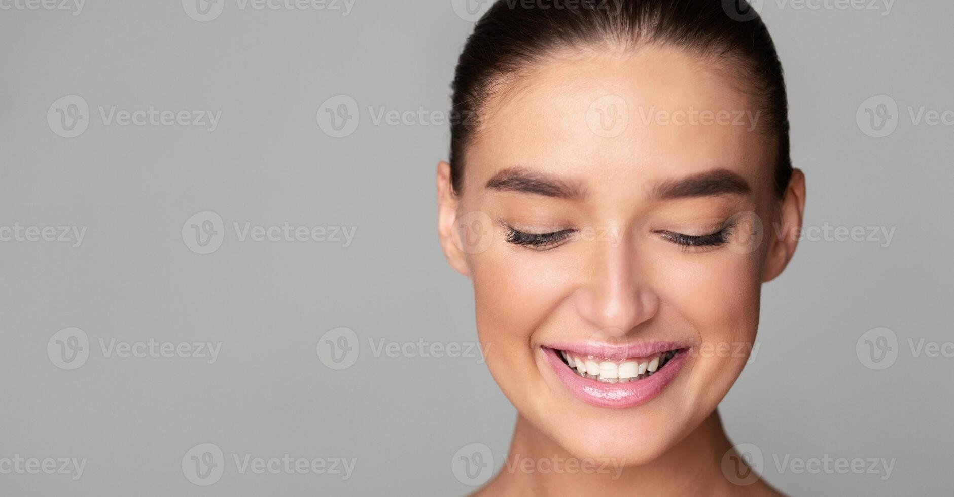 A young woman is smiling with her eyes closed in a joyful expression. Her face is illuminated by happiness as she enjoys a moment of bliss, copy space photo