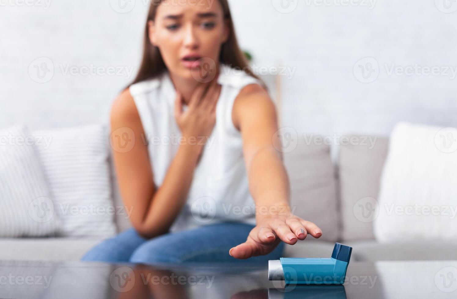 Girl Reaching For Asthma Inhaler Preventing Respiratory Depression Sitting On Couch At Home. Shallow Depth, Selective Focus photo